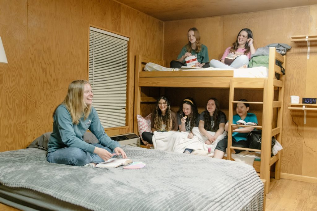 Several campers sitting on beds in a cabin
