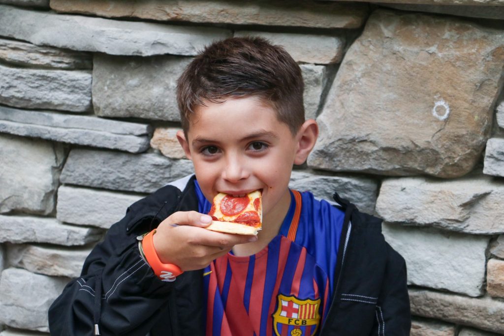 young boy eating a slice of pizza